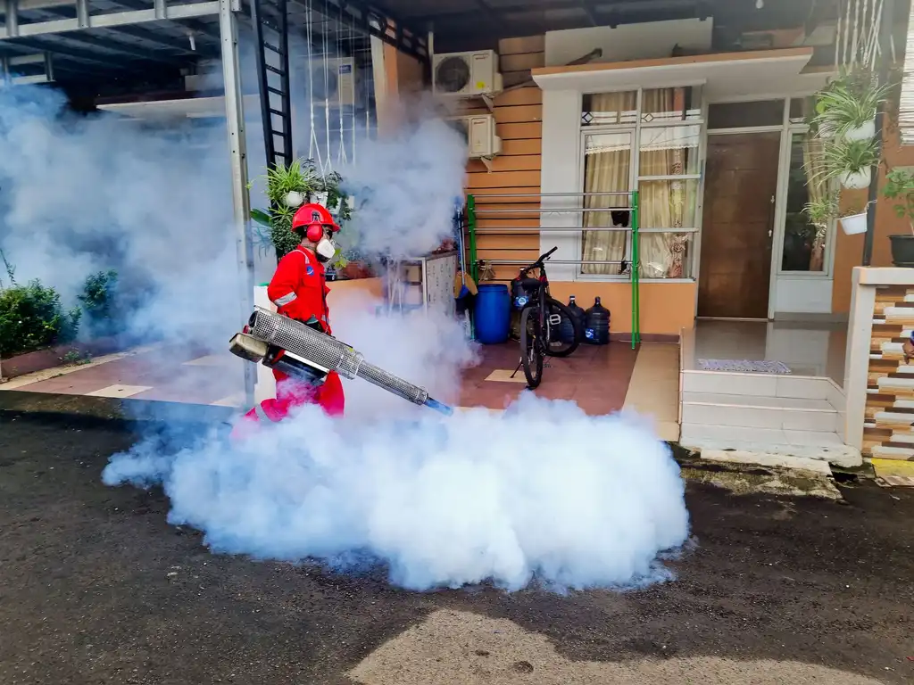 A pest control technician fogging outside a house