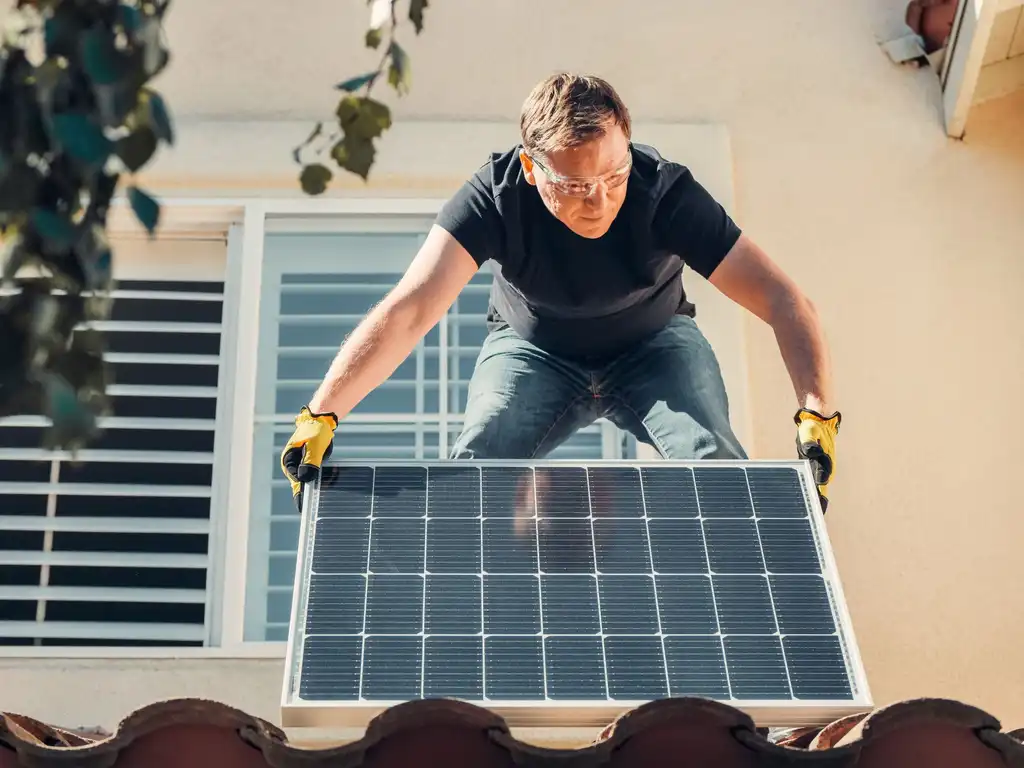 An installer fitting a solar panel on a house roof